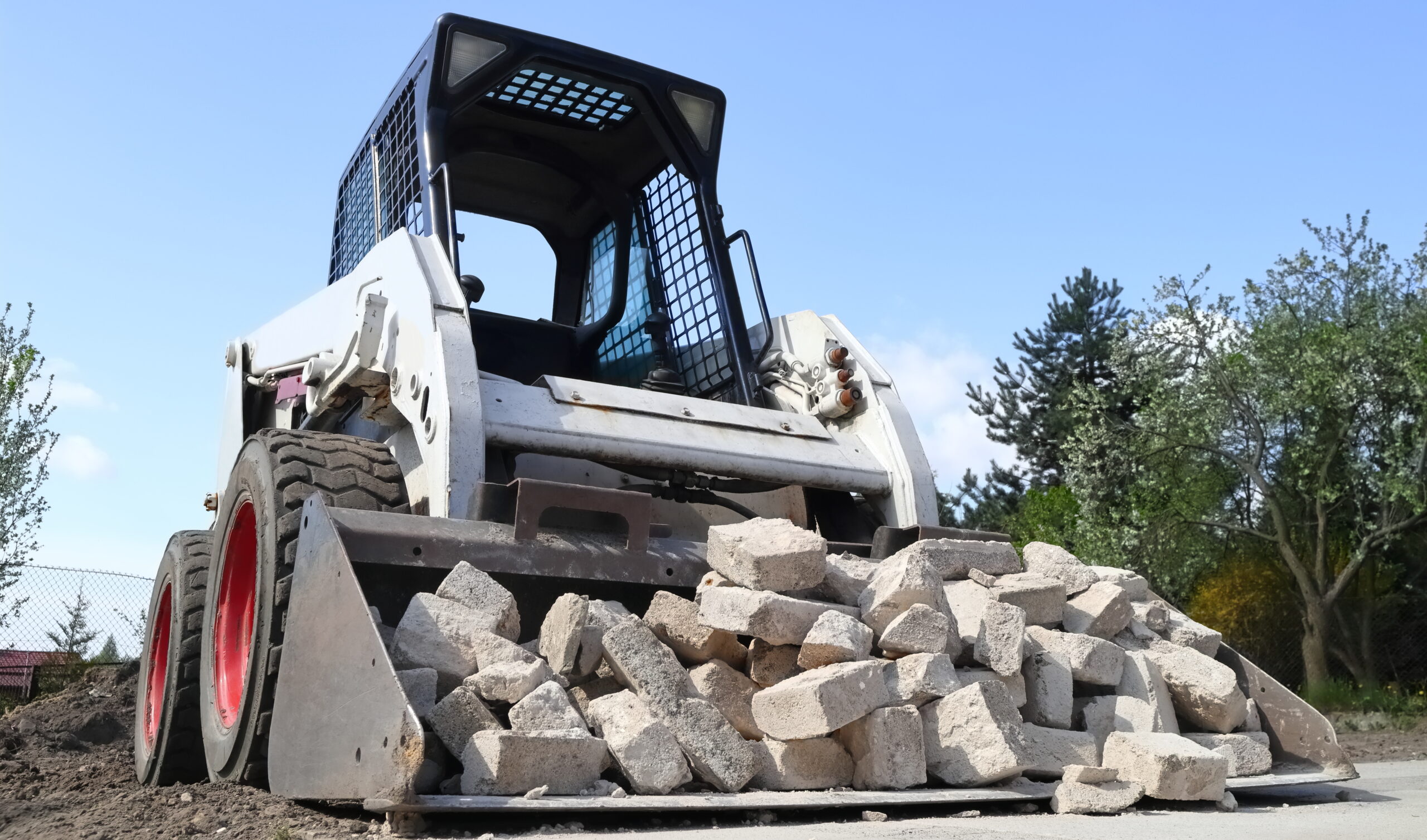 Skid steer loader for construction site with loading bucket filled with bricks.