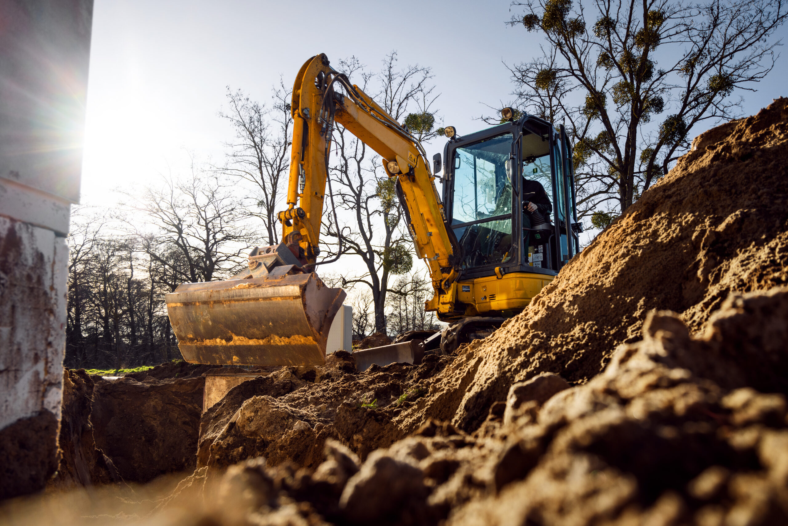 Mini excavator digging a trench next to a building
